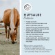 Ein Pferd weidet neben einer Anzeige für "Hufsalbe," einer Hufsalbe, die die Hufpflege, Feuchtigkeit und Schutz vor Austrocknung und Rissbildung fördert.
