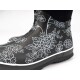 Schwarze Gummiregenstiefel mit weißen Blumenmustern, mit einem eleganten Design und einer weißen Sohle, vor einem weißen Hintergrund präsentiert.