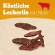 Köstliche Leckerlis mit Rind, mit verschiedenen Rindfleischgeschmack-Hundeleckerlis auf einem strukturierten Hintergrund.