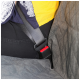 Nahaufnahme einer Person in einem schwarzen Shirt und gelbem Oberteil, sitzend mit angelegtem Sicherheitsgurt, teilweise von einer gepolsterten Sitzabdeckung verdeckt.