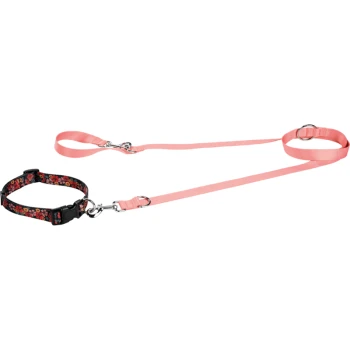 A pink pet leash with a floral-patterned black harness, featuring two clips and adjustable straps.