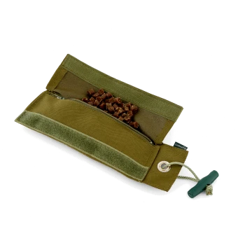 Olivgrüne Canvas-Tasche für Hundeleckerlis, Reißverschlussfach mit herausfallenden braunen Leckerlis, Klettverschlussklappe und grünem Kordelstopper; kein lesbarer Text.
