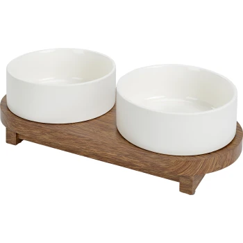 Weiße Keramik-Hundefutter- und Wasserschalen auf einem Holzständer, mit zwei runden Schalen und einer glatten Oberfläche.