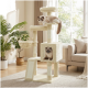 Cremefarbener mehrstöckiger Kratzbaum mit zwei flauschigen Katzen in einem sonnendurchfluteten Wohnzimmer neben einem Fenster, Topfpflanzen und beigem Sofa.