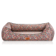 Bunt gemusterte Hundebett mit einem plüschigen Design und einem braunen Logoetikett, mit einem geometrischen Motiv in Rot, Blau und Grün.