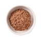 Schüssel mit Haustierfutter mit einer dicken, braunen, pâtéartigen Textur, vor einem hellgrünen Hintergrund.