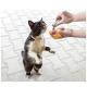 Chat noir et blanc sur les pattes arrière, reniflant pendant que des mains remplissent un jouet pour chat jaune orné d'un cœur rose et d'un texte noir.
