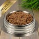 Eine Edelstahlschüssel für Haustierfutter, gefüllt mit hochwertigem Nassfutter für Hunde, mit einem goldenen "PREMIUM"-Etikett in der Ecke.