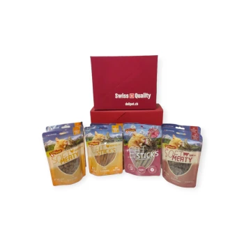 Czerwone pudełko oznaczone "Szwajcarska jakość" zawiera cztery paczki karmy dla zwierząt: dwie "Miękkie mięsne" i dwie "Cat Sticks" z obrazkami kotów.