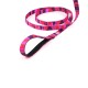 Bunte pinke und lila gemusterte Hundeleine mit einem bequemen Griff, flach auf einem weißen Hintergrund ausgelegt.