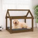 Ein glücklicher Golden Retriever, der auf einem grauen Kissen in einem Holz-Hundebett mit schrägem Dach liegt, in einem hellen Raum.