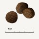 Drei runde, dunkelbraune Haustierfutter-Kibble-Stücke auf einem hellen Hintergrund, mit einem Lineal, das eine Skala von 1 cm anzeigt.