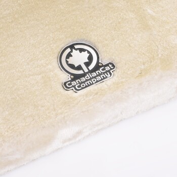 Eine weiche, cremefarbene Haustierdecke mit einem silbernen Logo der Canadian Cat Company, das ein Ahornblatt-Design zeigt.