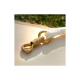 Nahaufnahme eines goldenen Metallclips, der an einem weißen geflochtenen Seil befestigt ist, auf einer hellen Holzoberfläche mit verschwommenem Grün im Hintergrund.