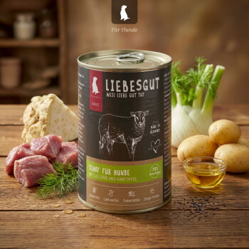 LIEBESGUT-Dose 'Schaf für Hunde' mit Aufschrift 'mit Sellerie und Kartoffel', auf Holz mit rohem Fleisch, Kartoffeln, Fenchel und Öl.