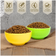 Eine Schüssel gefüllt mit Premium-Haustierfutter-Kibble, mit etwas Kibble, das auf eine Holzoberfläche gefallen ist, umgeben von grünen Grasakzenten.