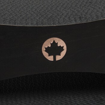 Nahaufnahme eines schwarzen Haustierprodukts mit einem kupferfarbenen Ahornblatt-Logo an der Seite, mit einer strukturierten Oberfläche darüber.