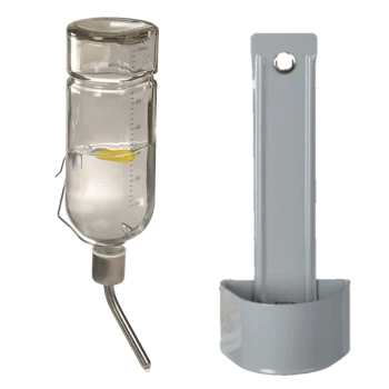 Bouteille d'eau en verre avec des marquages de mesure et un bec en métal, à côté d'un support en plastique gris pour la bouteille.