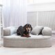 Ein hellgraues Hundebett mit einem plüschigen Design, das ein kleines Kissen enthält, und ein entspannter Hund, der bequem darauf liegt.