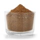Ein klarer Glasbehälter, gefüllt mit braunem Haustierergänzungspulver, das oben aufgetürmt ist, vor einem weißen Hintergrund.