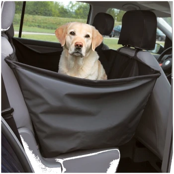 Een hond zit comfortabel in een zwarte autostoelhoes voor huisdieren, vastgezet op de achterbank van een voertuig, met een schilderachtig uitzicht naar buiten.