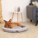 Ein gemütliches Hundebett in hellgrauer Farbe mit einem kleinen Hund, der darauf ruht, in einem modernen Wohnzimmer mit einem Beistelltisch und einer dekorativen Vase.