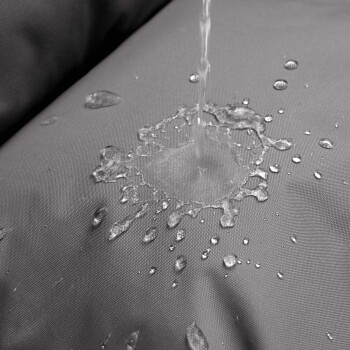 Wassertropfen spritzen auf einen grauen, wasserfesten Haustierbettstoff und zeigen dessen wasserdichte Eigenschaften.