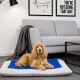 Ein flauschiger Hund liegt bequem auf einem plüschigen Haustierbett mit einem blau-grauen Design und ruht seinen Kopf auf der Kante in einem modernen Wohnzimmer.