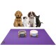 Eine lila Tiermatte mit zwei Futternäpfen, einem grauen und einem weißen, liegt vor vier Tieren: zwei Hunden, einem Kätzchen und einer schwarzen Katze.