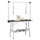 Ein gelber Labrador-Welpe liegt auf einem schwarzen Frisiertisch mit einem Metallrahmen, der zwei Überleinen und darunter Friseurwerkzeuge aufweist.