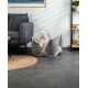 Ein kleiner weißer Hund sitzt bequem in einem stilvollen grauen Haustierbett, umgeben von moderner Möbeln und Dekor in einem gemütlichen Wohnzimmer.