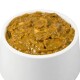 Eine weiße Tierfutterschüssel gefüllt mit dickem, bräunlich-grünem Nassfutter für Hunde, das eine stückige Textur zeigt.