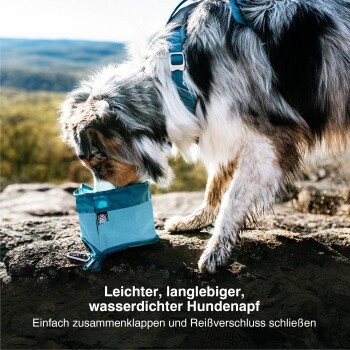 Ein Hund, der eine hellblaue, wasserdichte, zusammenklappbare Hundeschüssel auf einer felsigen Oberfläche schnüffelt, mit deutschem Text, der ihre Eigenschaften bewirbt.