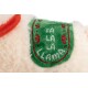 Close-up van een pluchen lama-speelgoed met een groene patch geborduurd met "Fa La La Llama" in witte en rode draad.
