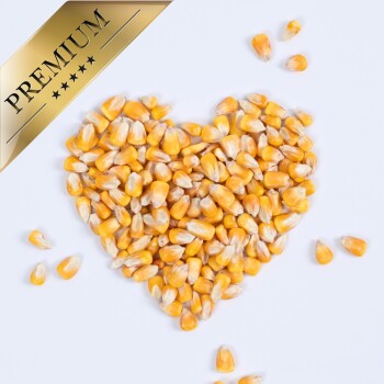 Herzförmige Anordnung von gelben Maiskörnern auf einem weißen Hintergrund, mit einem goldenen Banner 'PREMIUM' in der oberen Ecke.