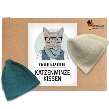 Eine Pappverpackung mit einem Etikett mit dem Text "KATER KASIMIR KATZENMINZE KISSEN" und zwei Katzenminzkissen, eines in Teal und eines in Creme.