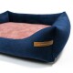 Marineblaues Haustierbett mit einem weichen rosa Zentrum und erhöhten Rändern, mit einem Lederschild, das "RexProduct.com" liest.