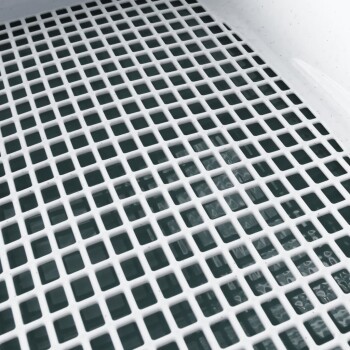 Eine Nahaufnahme eines weißen Kunststoffgittermusters über einer Wasseroberfläche, wahrscheinlich Teil eines Bade- oder Pflegeprodukts für Haustiere.