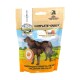 Hundeleckerlipackung mit der Aufschrift 'Complete-Snack' und einer Silhouette eines Hundes, mit einem Hintergrund aus einer grasbewachsenen Landschaft und deutschem Text.