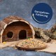 Ein Holzhaustierhaus neben einer Schüssel mit gemischtem Tierfutter, mit dem Text "Ganzjahresfütterung" in einem kreisförmigen Design darüber.