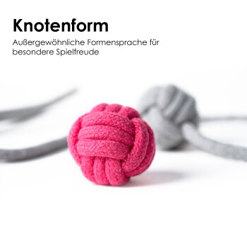 Zwei bunte Haustierspielzeuge aus weichem Stoff: ein rosa Knotenball und ein grauer Knotenball, verbunden durch ein graues Band.