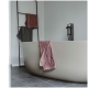 Ein modernes Badezimmer mit einer eleganten, geschwungenen freistehenden Badewanne, über deren Rand ein pinkfarbener Handtuch hängt, und einem schwarzen Handtuchhalter im Hintergrund.