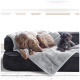 Ein brauner Hund schläft auf einer grauen Decke neben einem kleinen schwarzen Pudel auf einem schwarzen Sofa, mit einer hellen Wand im Hintergrund.