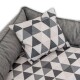 Graues Tierbett mit passendem Kissen im geometrischen Muster mit schwarzen, weißen und grauen Dreiecken auf schwarzem Hintergrund.