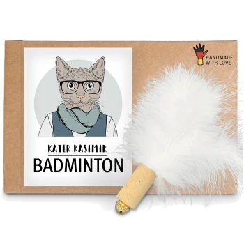 Ein Kartonpaket mit einer Cartoon-Katzenillustration und dem Text "KATER KASIMIR BADMINTON" sowie einem weißen Feder-Spielzeug, das angebracht ist.