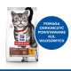 Torba z jedzeniem dla kotów z szarym tabby, oznaczona 'Hill's Science Plan Hairball Indoor', z niebieskim okręgiem informującym 'Pomaga zmniejszyć kulki włosowe.'