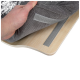 Une main soulève une housse en tissu gris d'une base de lit pour animaux en bois, montrant le mécanisme de fixation en dessous.