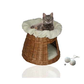 Ein gemütliches Korb-Katzenbett mit einem weichen cremefarbenen Kissen, mit einer getigerten Katze, die oben liegt, und zwei Spielbällen daneben.