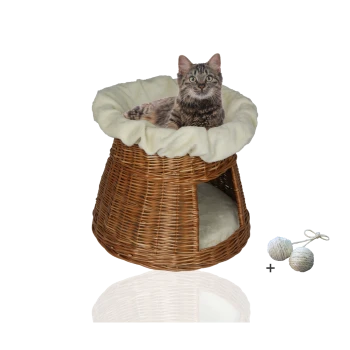 Ein gemütliches Korb-Katzenbett mit einem weichen cremefarbenen Kissen, mit einer getigerten Katze, die oben liegt, und zwei Spielbällen daneben.