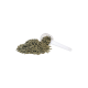 Ein klarer Löffel liegt neben einem Haufen grüner, pelletförmiger Haustierfutter auf einem weißen Hintergrund.